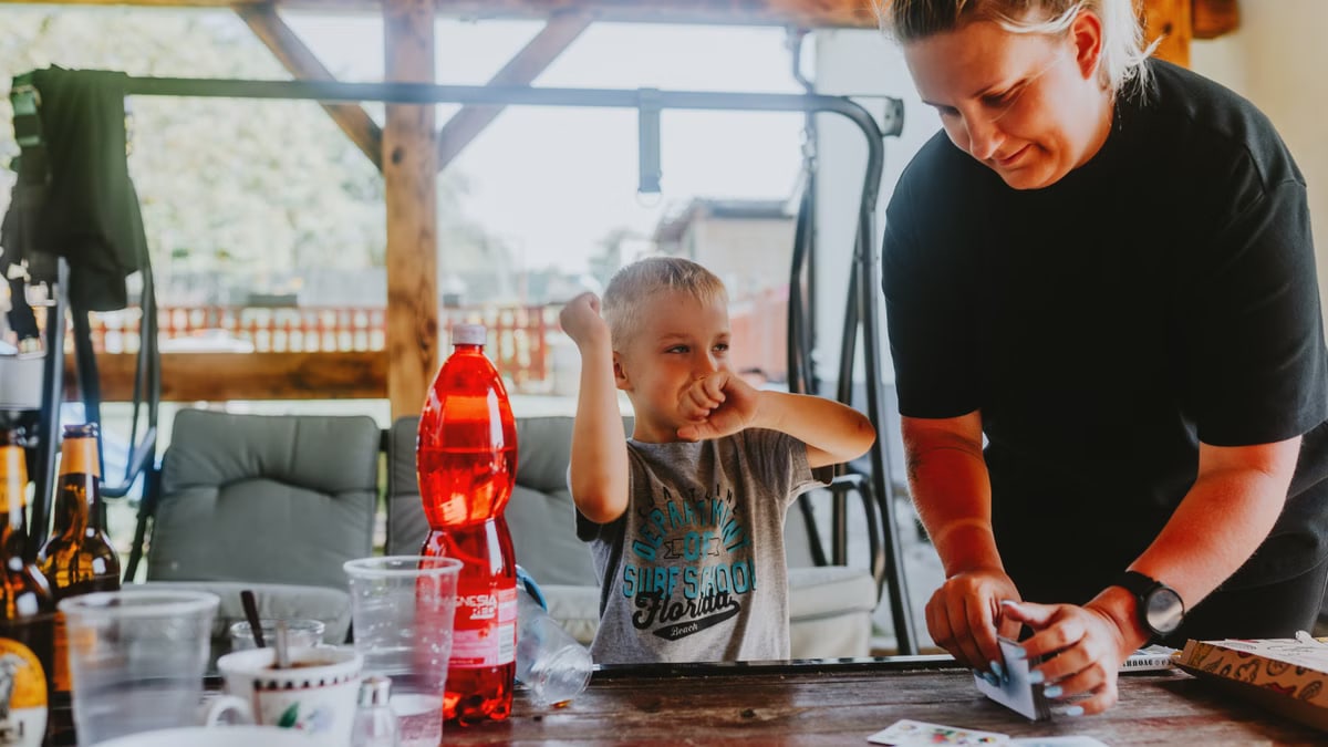 A cheerful moment of a mother and child playing cards outdoors in a backyard.